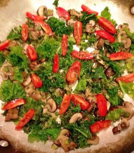 The fritatta topped with scatters kale leaves red pepper slices and mushrooms