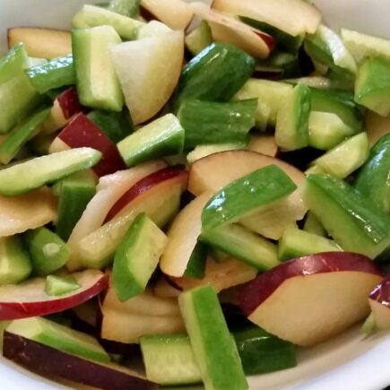 Choped plum and cucumbers tossed together in a bowl