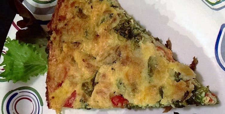 Slice of frittata on a paper plate viewed from above