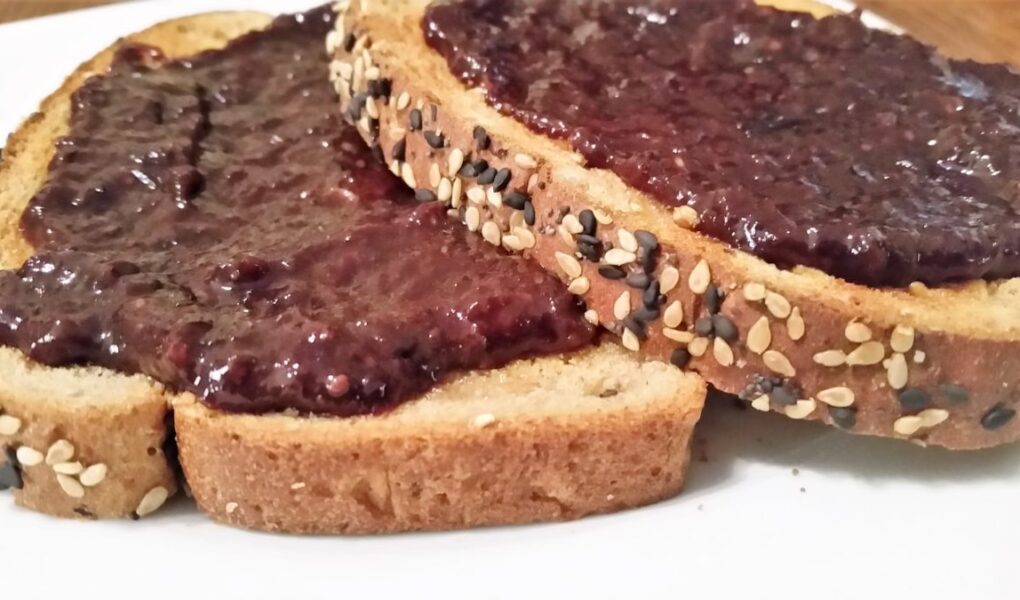 LS Grape-Cherry Jam spread on two slices of sesame toast on a white salad plate