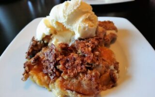 Peaches and Cream Cobbler on plate, topped with scoop of vanilla ice cream