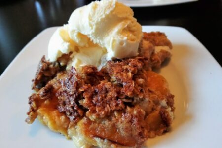 Peaches and Cream Cobbler on plate, topped with scoop of vanilla ice cream